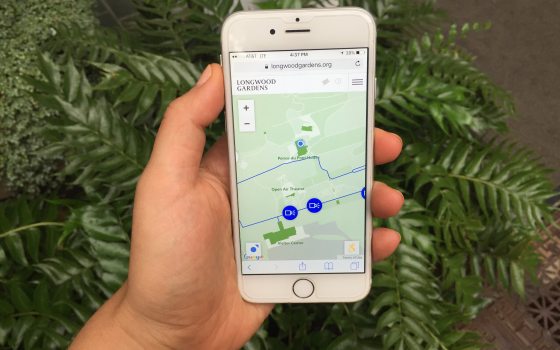 A person holding a cell phone showing a garden map.